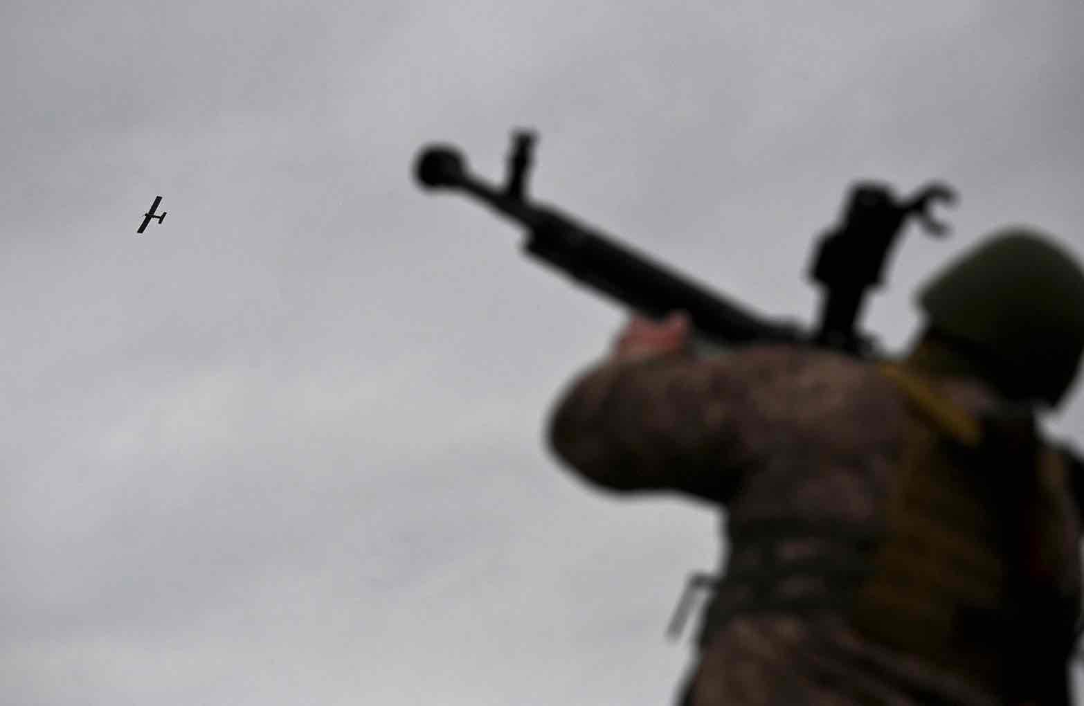 A Ukrainian serviceman aims a machine gun as a drone flies