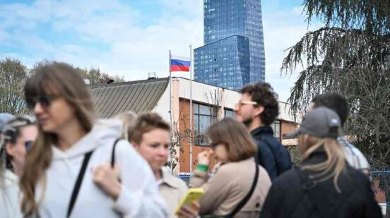 Voters queue outside a polling station set up in a Russian Embassy School as they wait to vote on the day of Russia's presidential election, in Belgrade