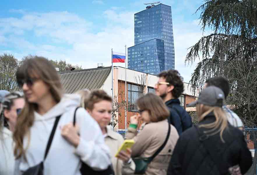 Voters queue outside a polling station set up in a Russian Embassy School as they wait to vote on the day of Russia's presidential election, in Belgrade