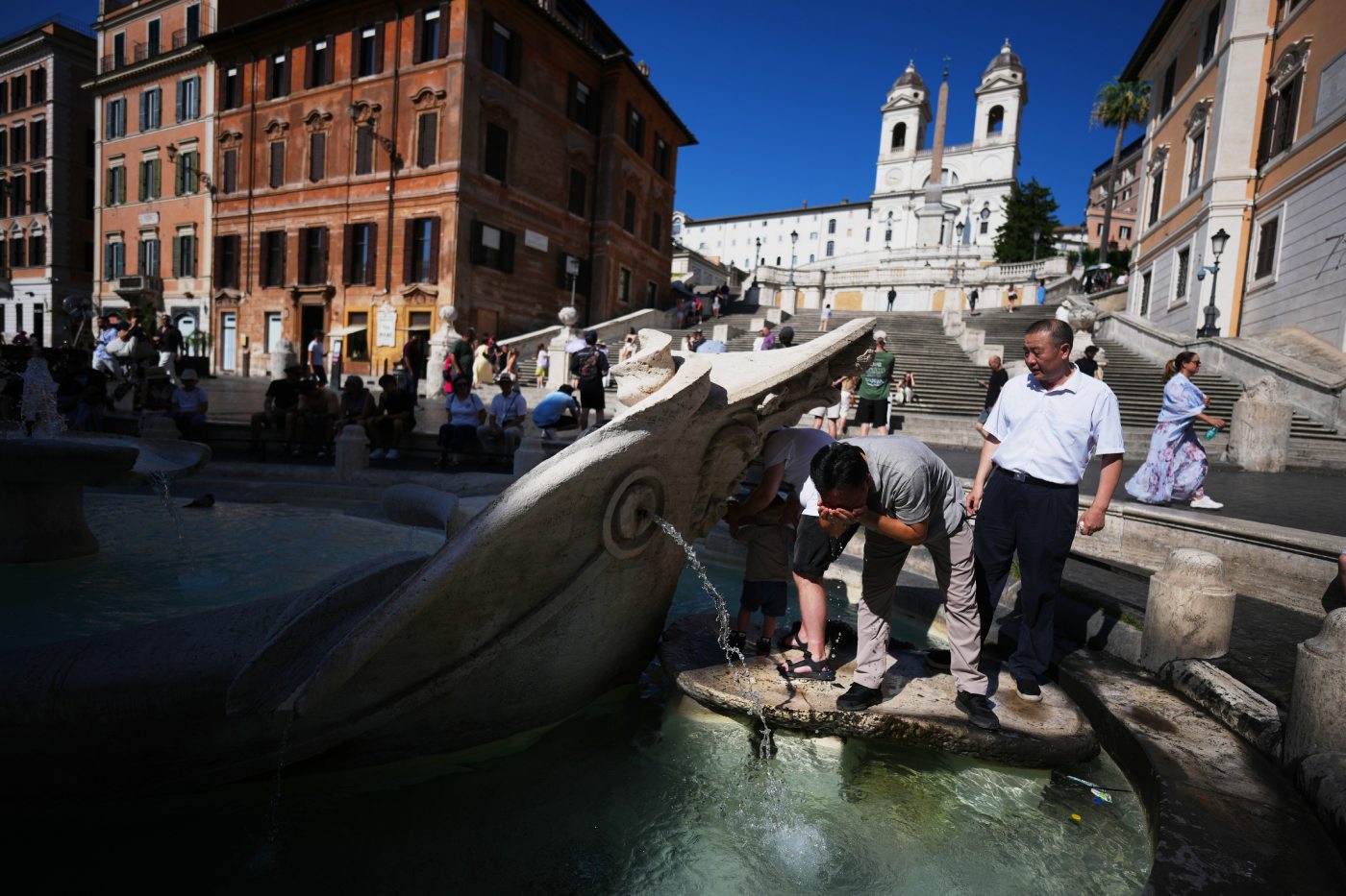 People refresh at the Barcaccia Fountain in front of Rome's Spanish Steps, Wednesday, July 15, 2026. (AP Photo/Andrew Medichini)