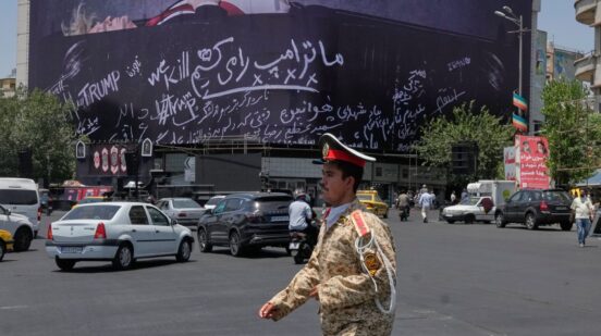 An army cadet walks past a billboard bearing anti-Trump messages, including the phrase